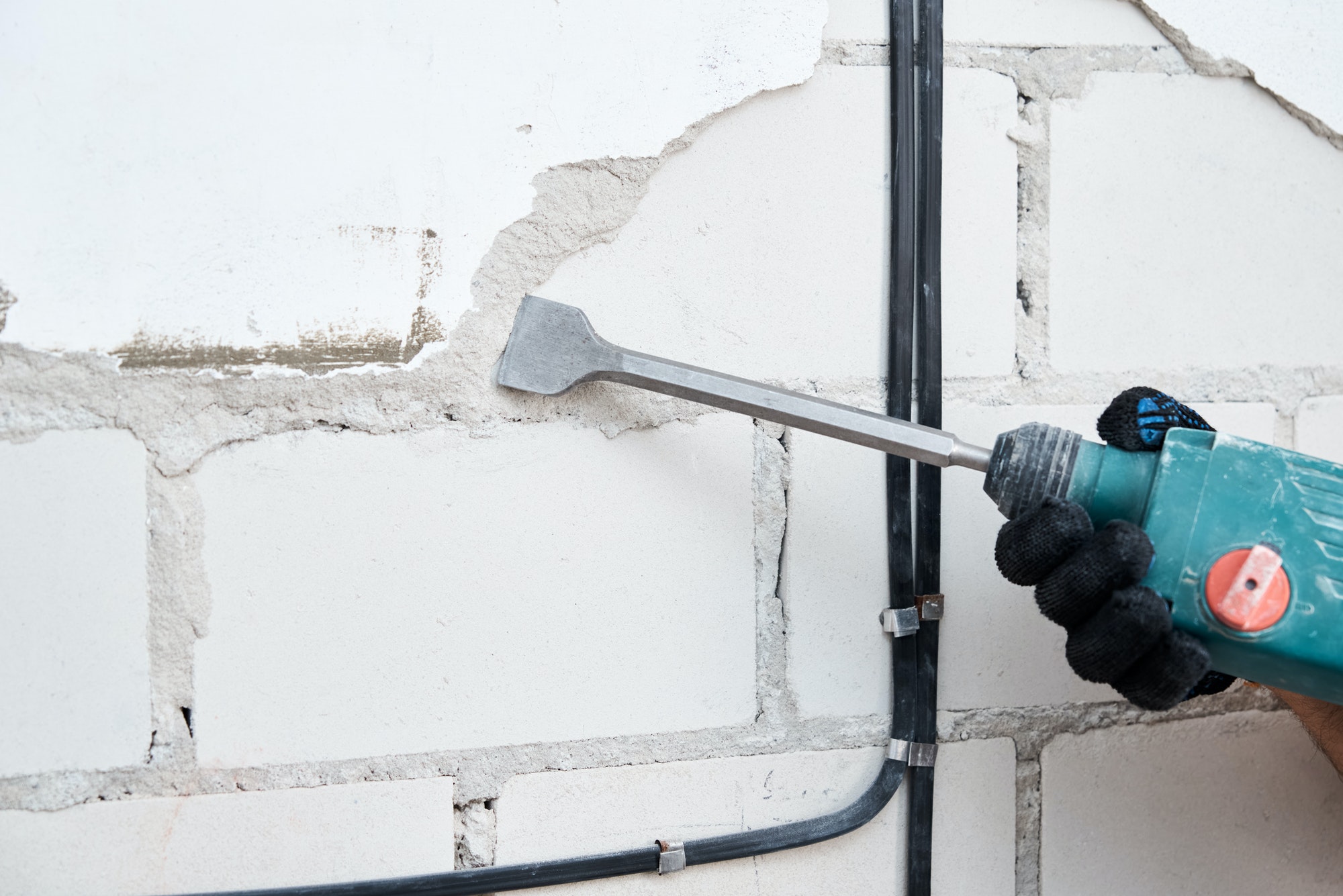 Man with demolition hammer remove stucco from wall. Renovation concept